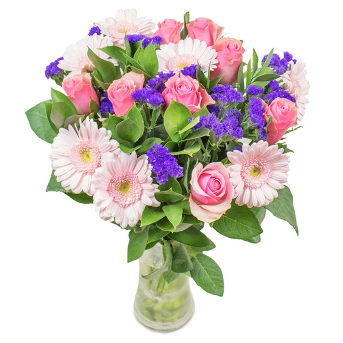 A beautifully balanced bouquet, arranged in a clear glass vase and set against a pristine backdrop, showcases the artistry of Blackheath florists. It features a captivating focal point of seven to nine pink roses, each with their signature spiral centers, some petals just beginning to unfurl, hinting at new beginnings and lasting affection. Nestled among them are five to seven soft pink gerbera daisies, their broad, numerous petals radiating outward and centers shaded almost white, inviting the light like flowers blooming on the fringe of Blackheath Park. Wisps of vivid purple statice flowers add dynamic contrast and rich texture, recalling wildflowers found in the margins of Greenwich Park. Deep green foliage provides a lush, lively base, framing the pinks and purples with abundant freshness. The clear glass vase, with visible stems and fresh water, offers a natural, unpretentious finish, making this bouquet suitable for special occasions-birthdays, anniversaries, Mother's Day-or simply as a stylish accent for a home or office in Blackheath. This arrangement, prepared by skilled local hands, celebrates nature's joy and tender affection, crafted to be delivered across the village and neighbouring areas.