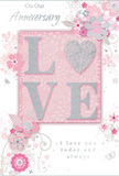 Resting flat as though ready to be slipped into an envelope, this anniversary card celebrates enduring romance with a palette of soft pastel pinks, muted greys, and gentle silvers that echo the calm of an evening walk through Blackheath. At its centre, the word LOVE stands proud in raised, softly sparkling glitter, each letter catching the light with a subtle sheen. The letter O is transformed into a shimmering silver heart, distinct in texture yet perfectly integrated into the word, like a cherished memory nestled within everyday life. Surrounding this focal point, delicate blooms in blush and mauve tones appear to unfurl across the card in an almost watercolour softness. Their outlines and shading are fine and fluid, suggesting light brushstrokes rather than heavy lines, much like the careful touch a florist uses when arranging fragile petals. Between the blossoms, slender swirls, dotted flourishes, and tiny butterfly motifs bring a sense of movement and quiet joy, reminiscent of a gentle breeze through a spring garden. Above and below the central design, the words On Our Anniversary and I love you today and always are written in elegant, understated script, the loops of the letters echoing the curves of the vines and stems. The overall effect is that of a tender keepsake, poised between simplicity and refinement, as if it had been chosen to accompany a soft, romantic bouquet ordered for same-day delivery across Blackheath's tree-lined streets, marking a shared journey that feels both intimate and profoundly cherished.